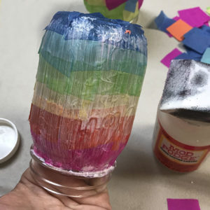 Painting mod podge over tissue paper on mason jar